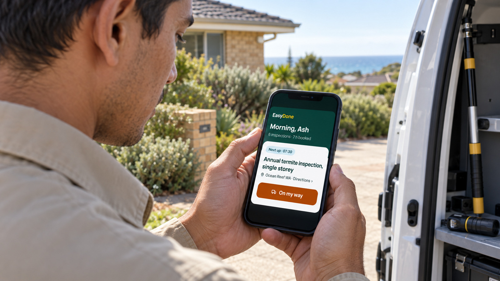 A pest inspector checks an Ocean Reef termite inspection in EasyDone on his phone beside a service van.